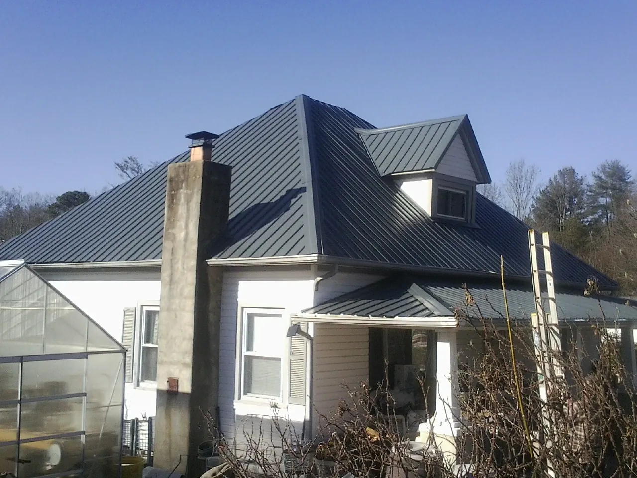 Dark blue standing seam metal roof on a white farmhouse with dormer — Slate & Tile Roof Repair by Roofing Brothers in Strabane