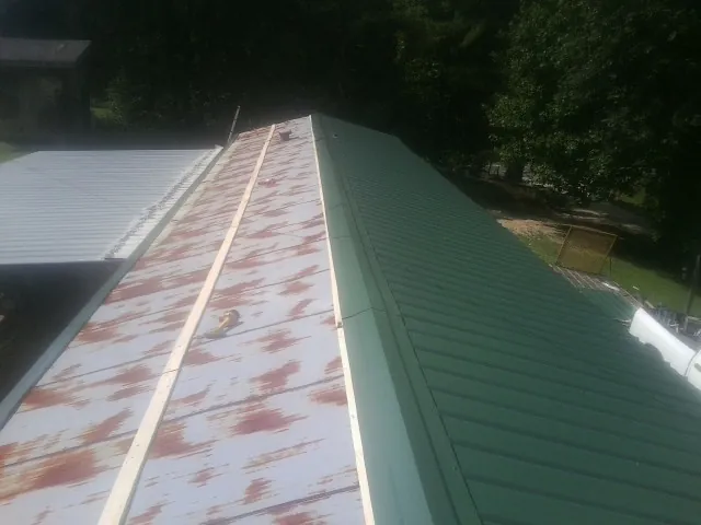 Old rusted panels beside newly installed green metal roofing — Wind Damage Roof Repair by Roofing Brothers in Strabane