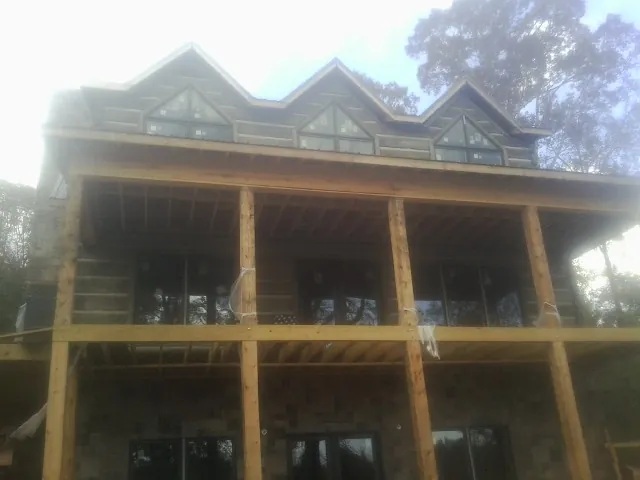 Dormers and porch framing on a large log home under construction — Roof Coating work by our crew in Strabane