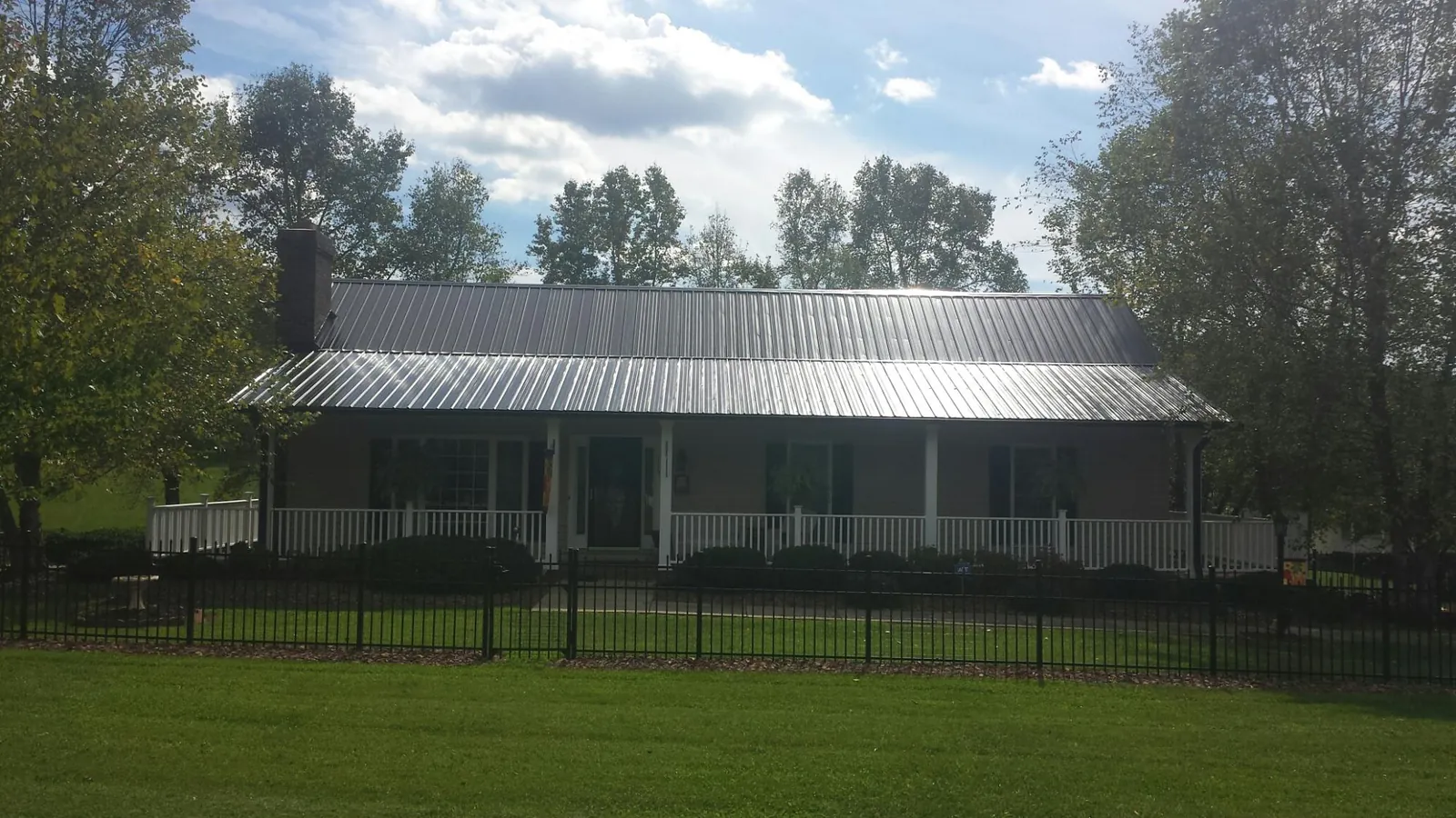 Gray metal roof on a brick ranch with a full width front porch — Gutter Guard Installation work by our crew in Strabane