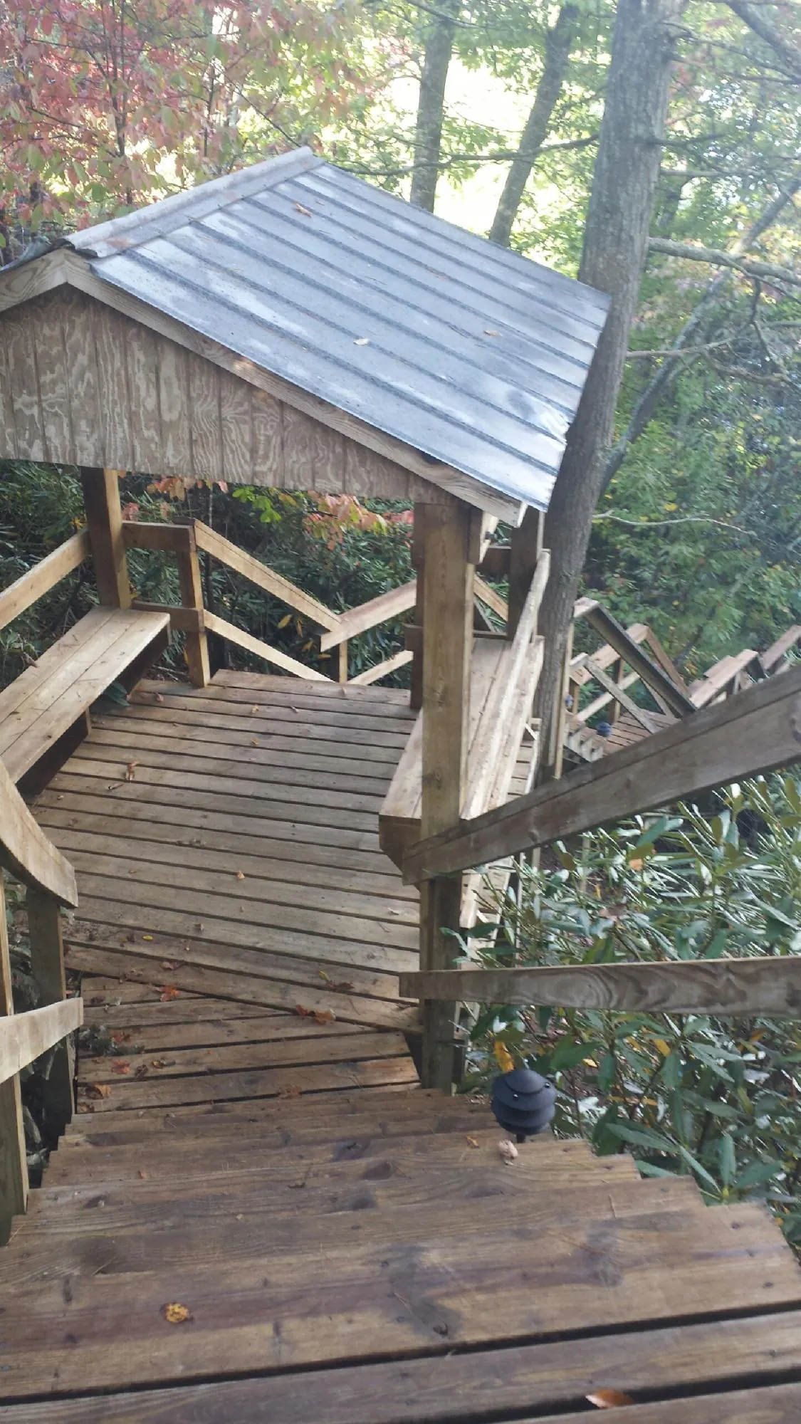 Metal roofed shelter over wooden steps on a wooded walkway — Skylight Repair & Installation work by our crew in Strabane